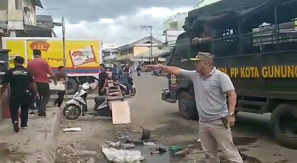 Salah satu oknum Satpol PP Kota Gunungsitoli, MZ (baju putih pakai topi) melempar buah nanas milik pedagang kaki lima di atas truk/foto:istimewa