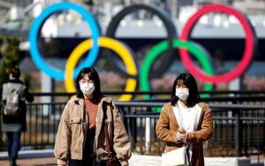 Dua wanita memakai masker terlihat sedang berjalan di pusat Kota Tokyo dengan latar belakang logo Olimpiade, beberapa waktu lalu. Pemerintah Jepang mulai ragu bisa menyelenggarakan Olimpiade 2020 tahun ini. (AFP/DAILY MAIL)