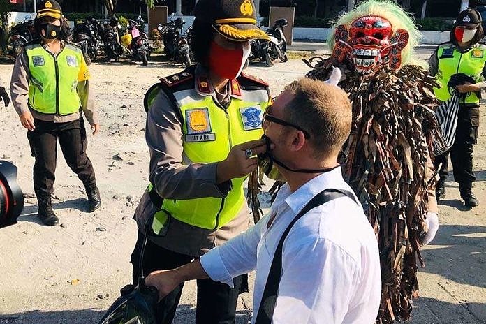 Aparat di Bali memberikan masker untuk turis yang tidak mengenakan - Foto :Ist